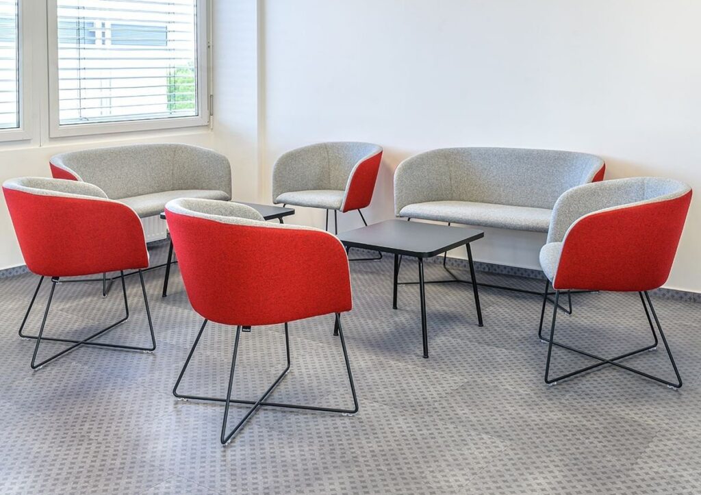 Red chairs in a social space around a coffe table.